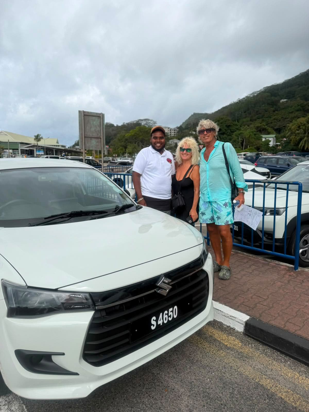 Visitors meeting a Sweet Car Hire team member beside a white Suzuki